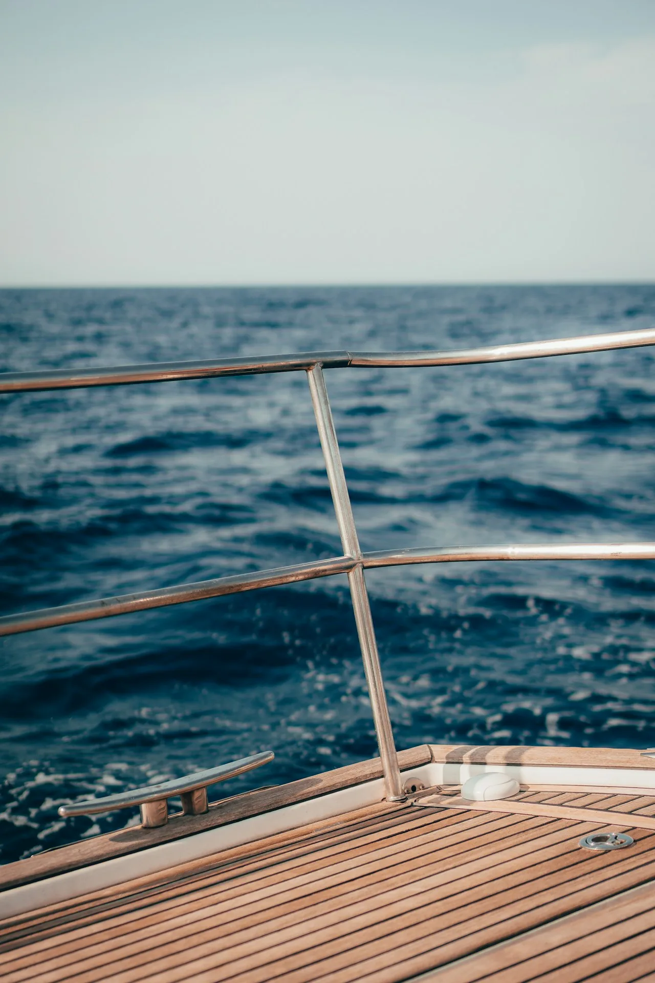 Pont en teck et balcon inox d'un bateau impeccablement entretenu devant la mer