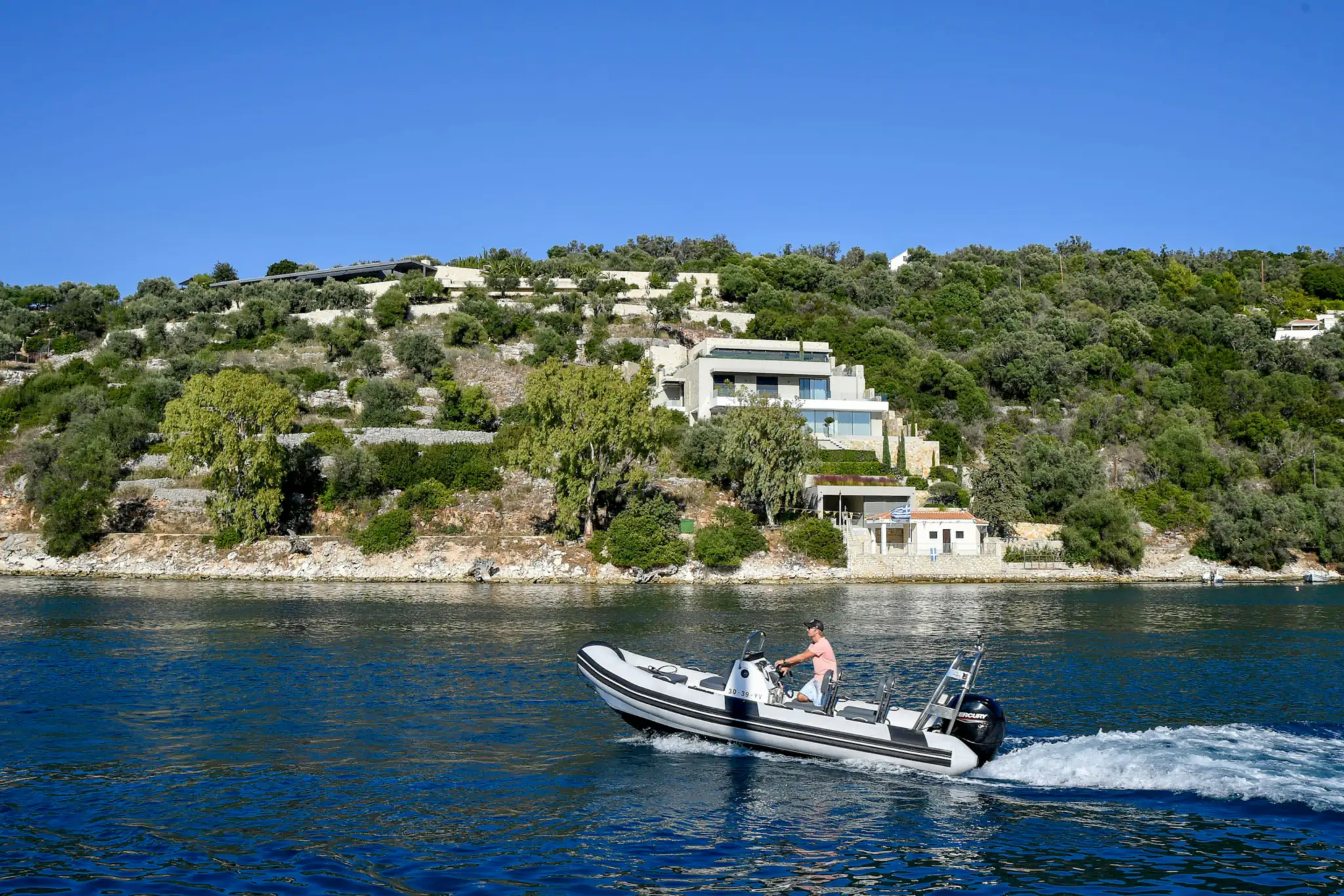 Semi-rigide naviguant le long d'une côte méditerranéenne bordée de villas